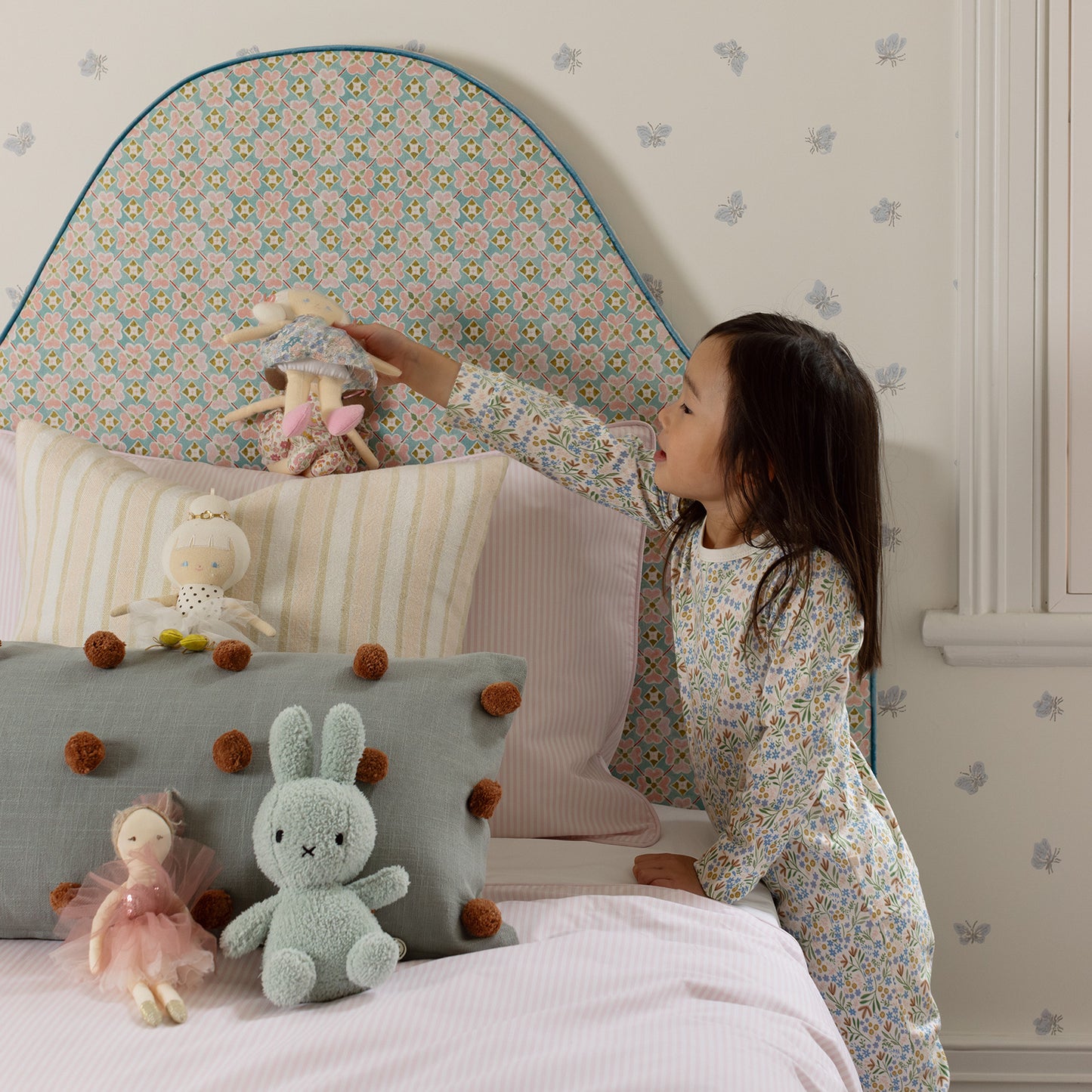 little girl playing with toys on her bed